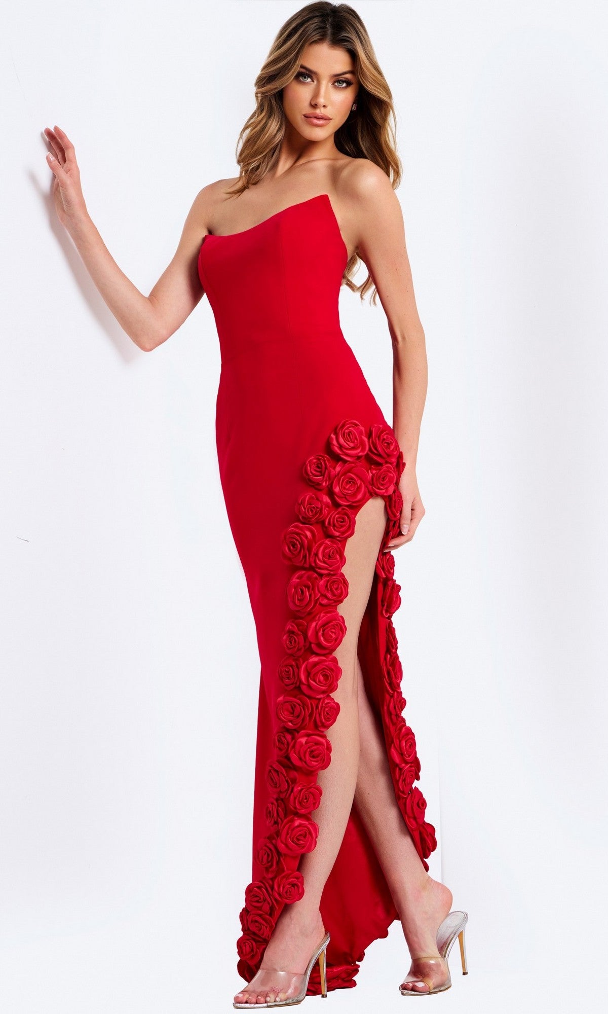A woman poses in the Jovani 47798 long prom dress with a strapless, fitted column silhouette, thigh-high slit with 3D floral appliques, paired with clear high heels.